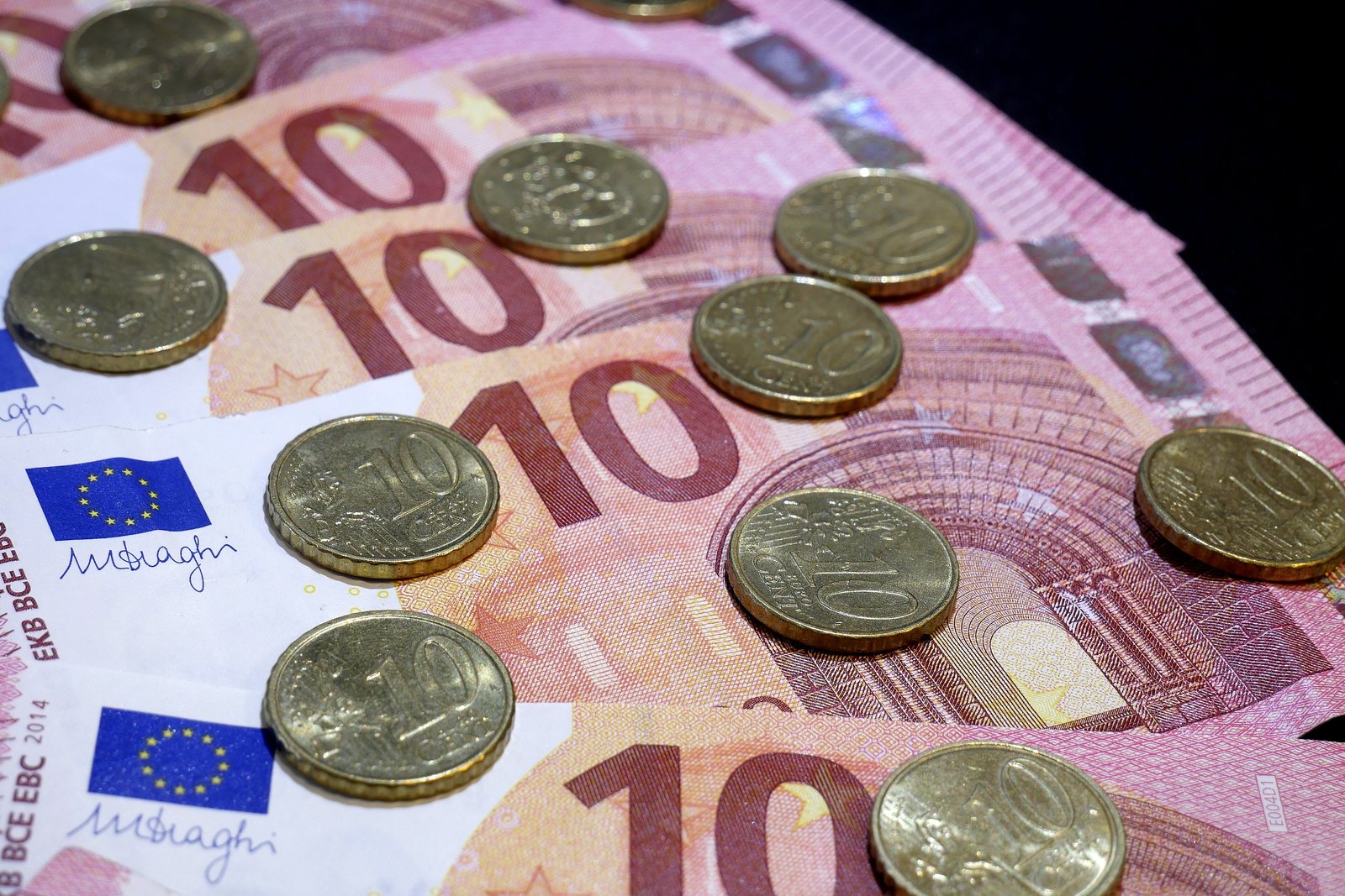 Euro-Münzen und Geldscheine liegen auf einem Tisch.