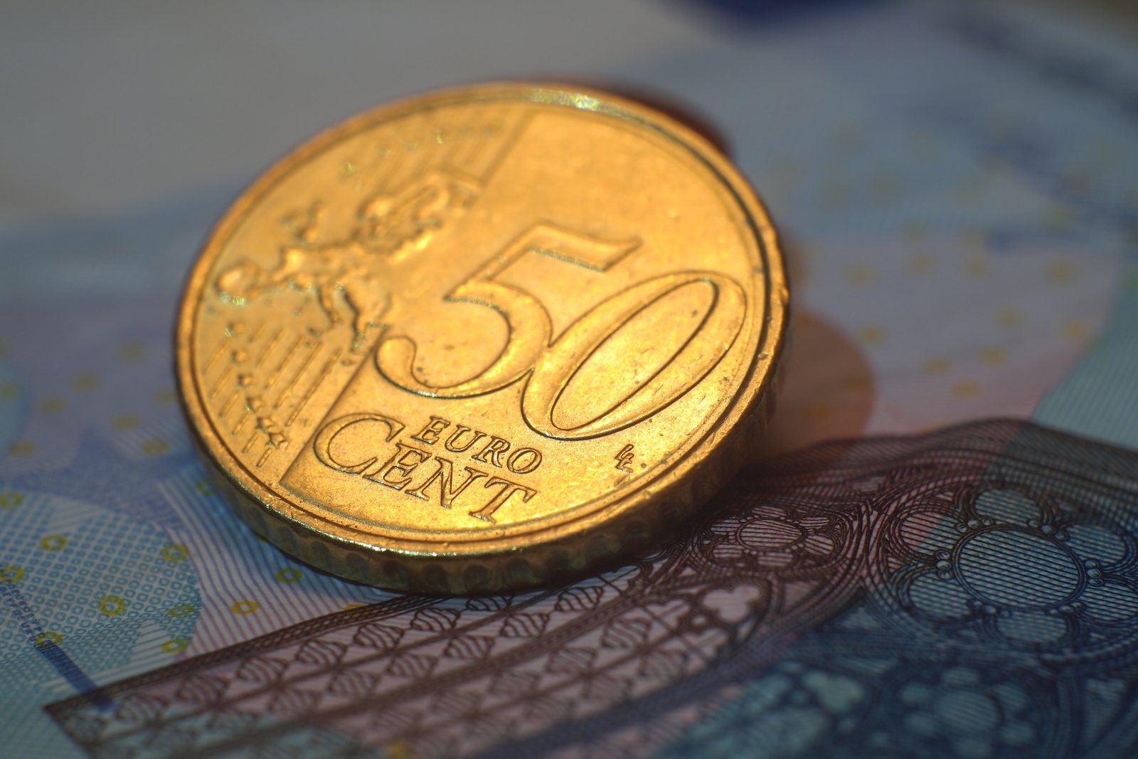 Eine 50-Cent-Münze liegt auf einem Euro-Geldschein.