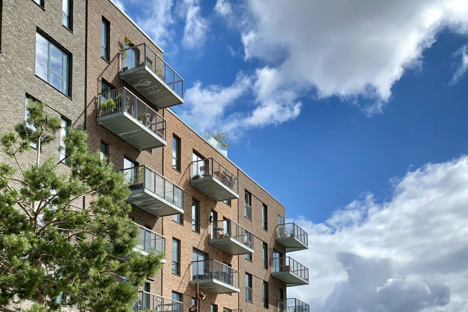 Ein Wohnhaus aus Ziegeln mit Balkonen unter blauem Himmel
