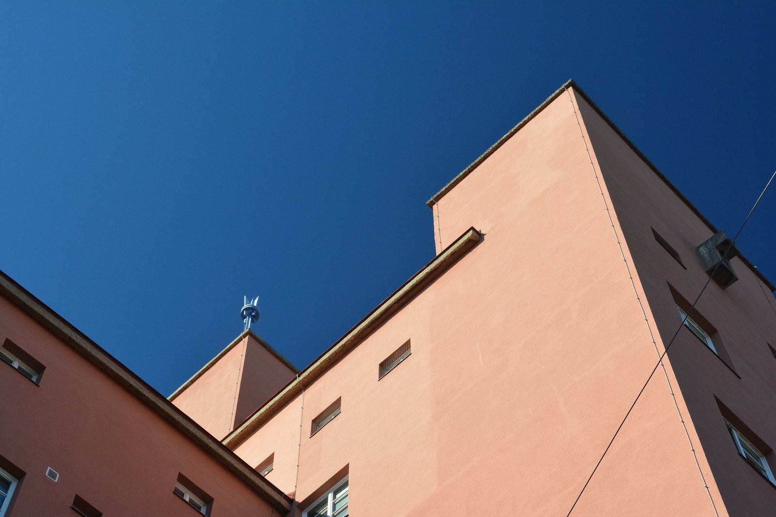 Modernes Wohngebäude mit rosafarbener Fassade und klarem Himmel.